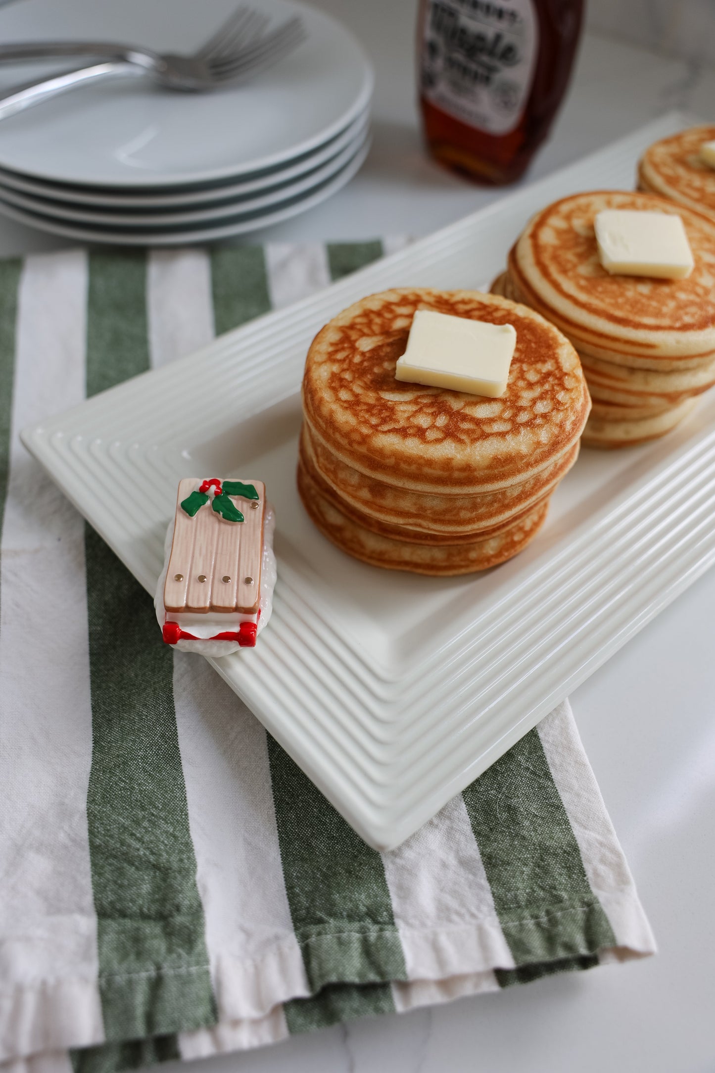 Stack of pancakes with butter on a white plate, with a vintage sled mini.
