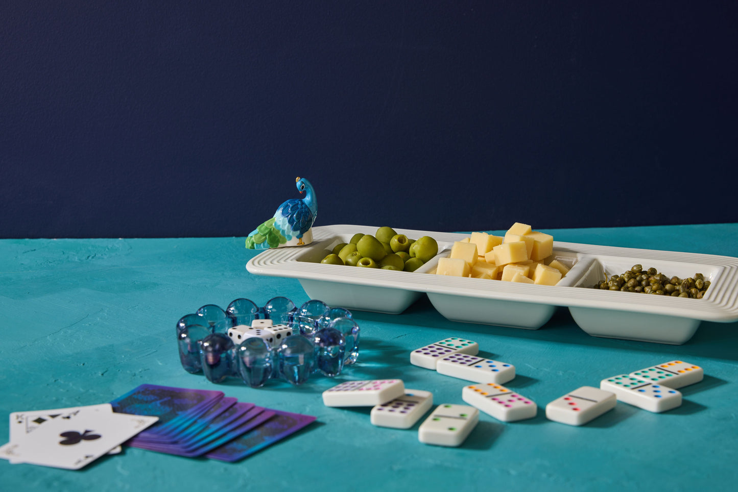 Assorted board game components including dice, cards, and dominoes on a blue surface with a dark background.