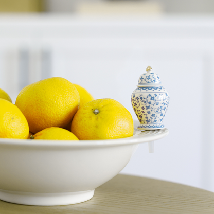 blue and white ginger jar mini with a gold top on top of a white bowl filled with lemons
