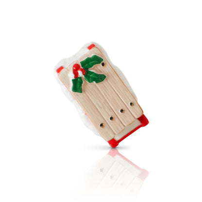 Small decorative sled mini with red runners and holly leaves on a white background