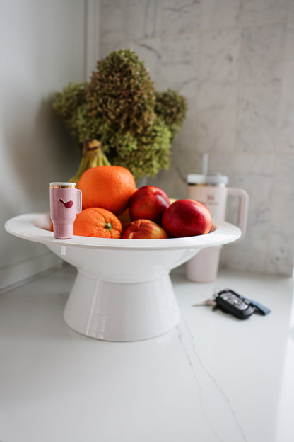 Fruit bowl with apples, oranges, and bananas on a white surface.