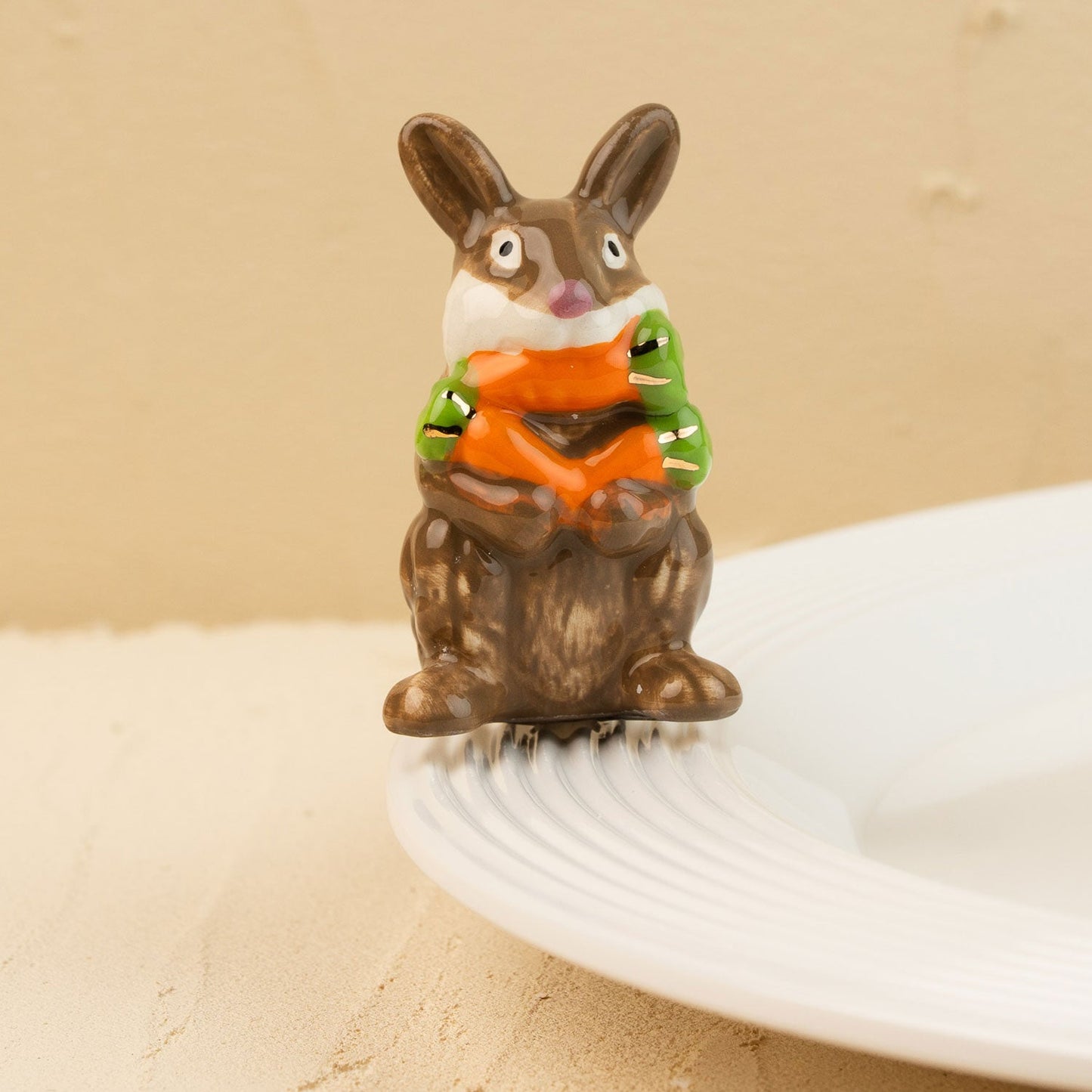 Decorative rabbit mini holding a carrot on a beige background