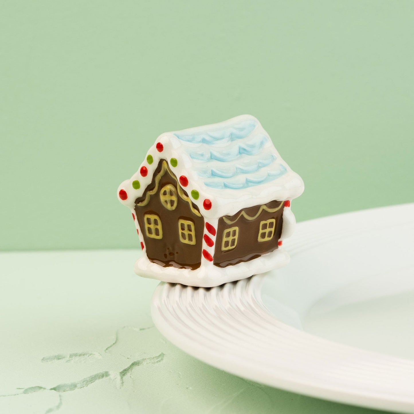 Gingerbread house mini  on a white plate with a green background