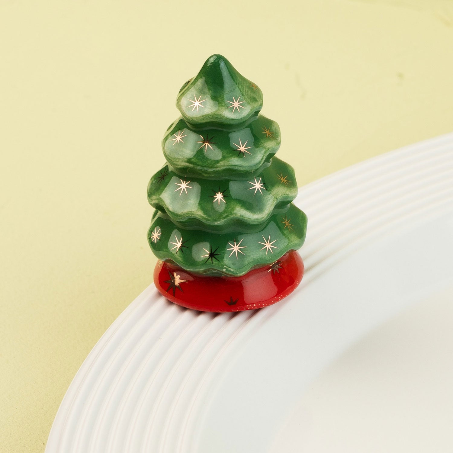 Decorative green Christmas tree mini with star patterns on a white surface and light green background