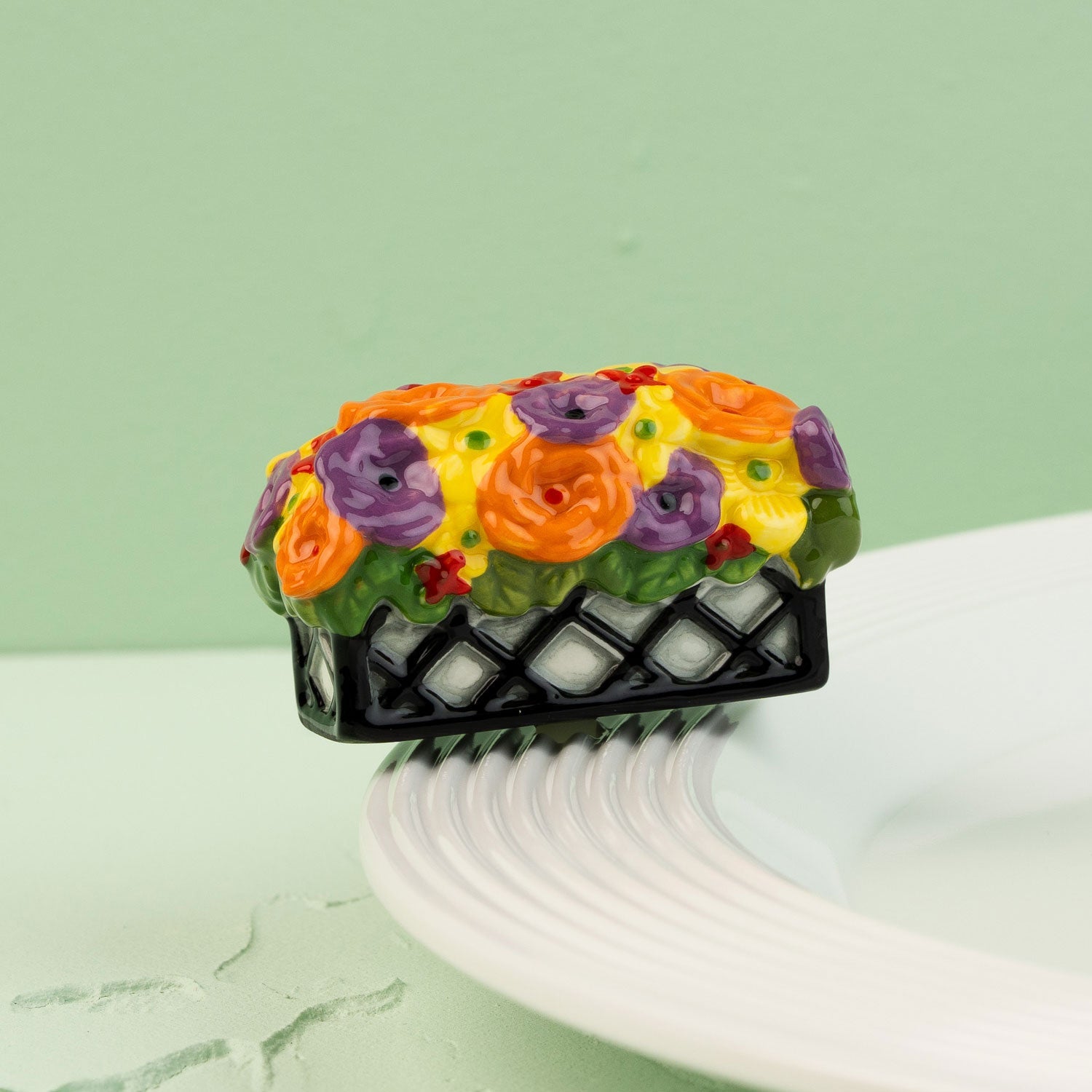 Colorful floral mini on a black flower  box on a white plate with a green background