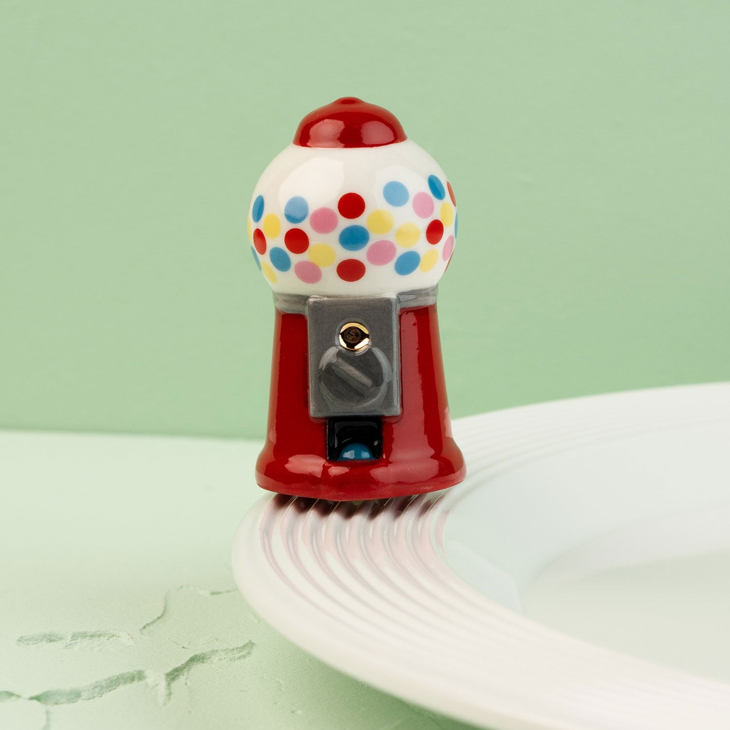 mini gumball machine with colorful polka dots on a light green background