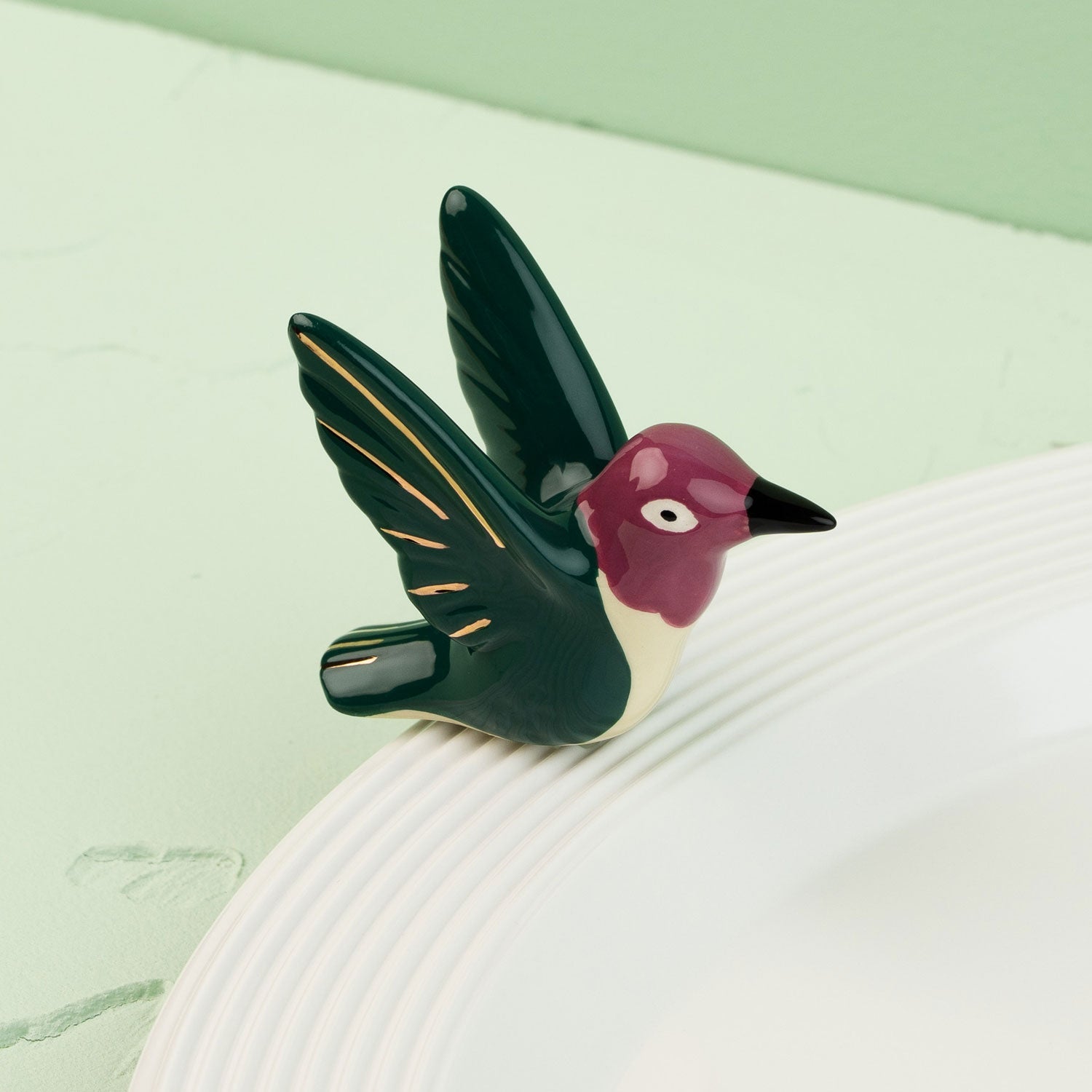 hummingbird mini on a white surface with a green background