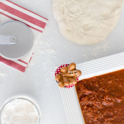 top view of a bread basket mini on a square holder filled with pizza sauce.