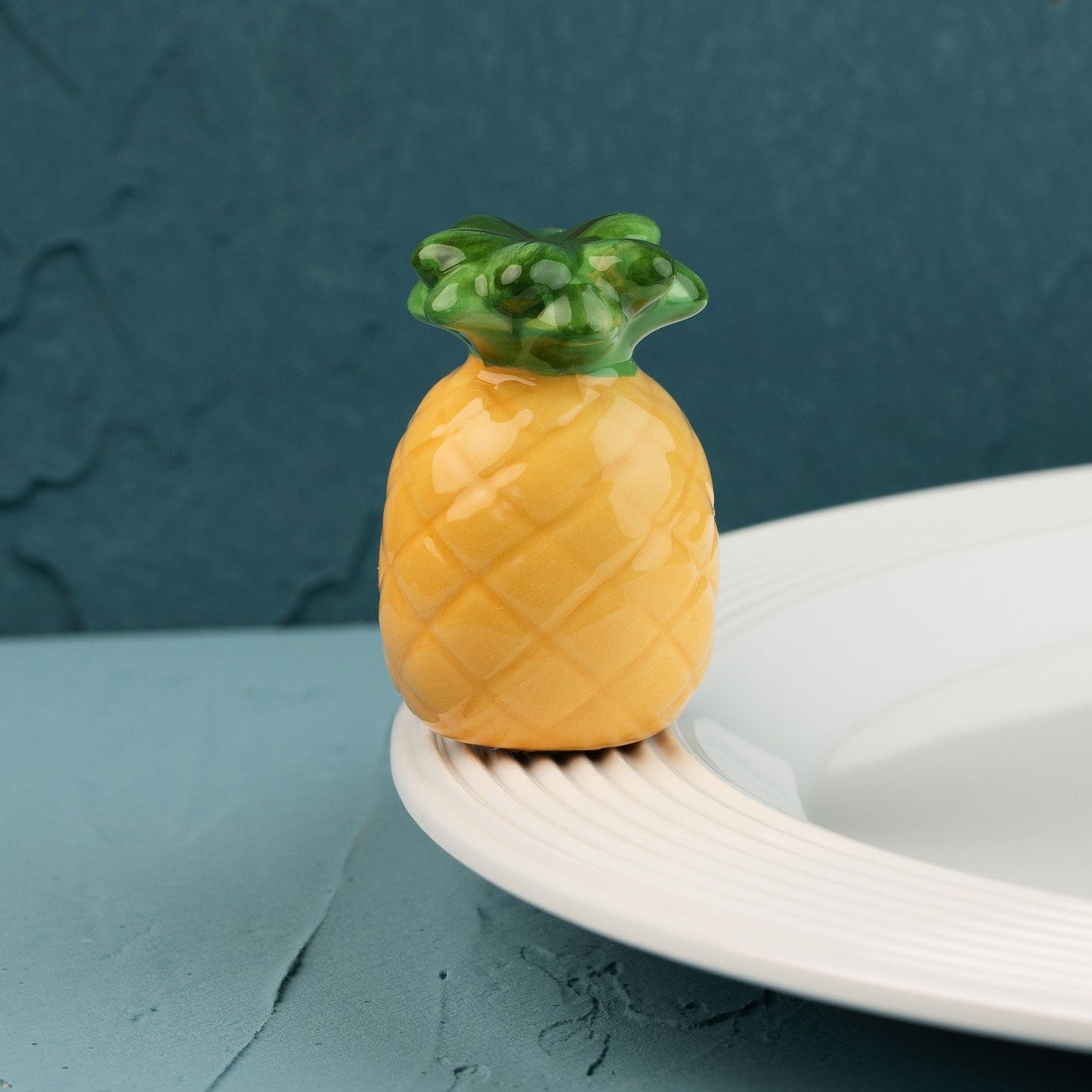 Pineapple-shaped mini on a white plate against a teal background
