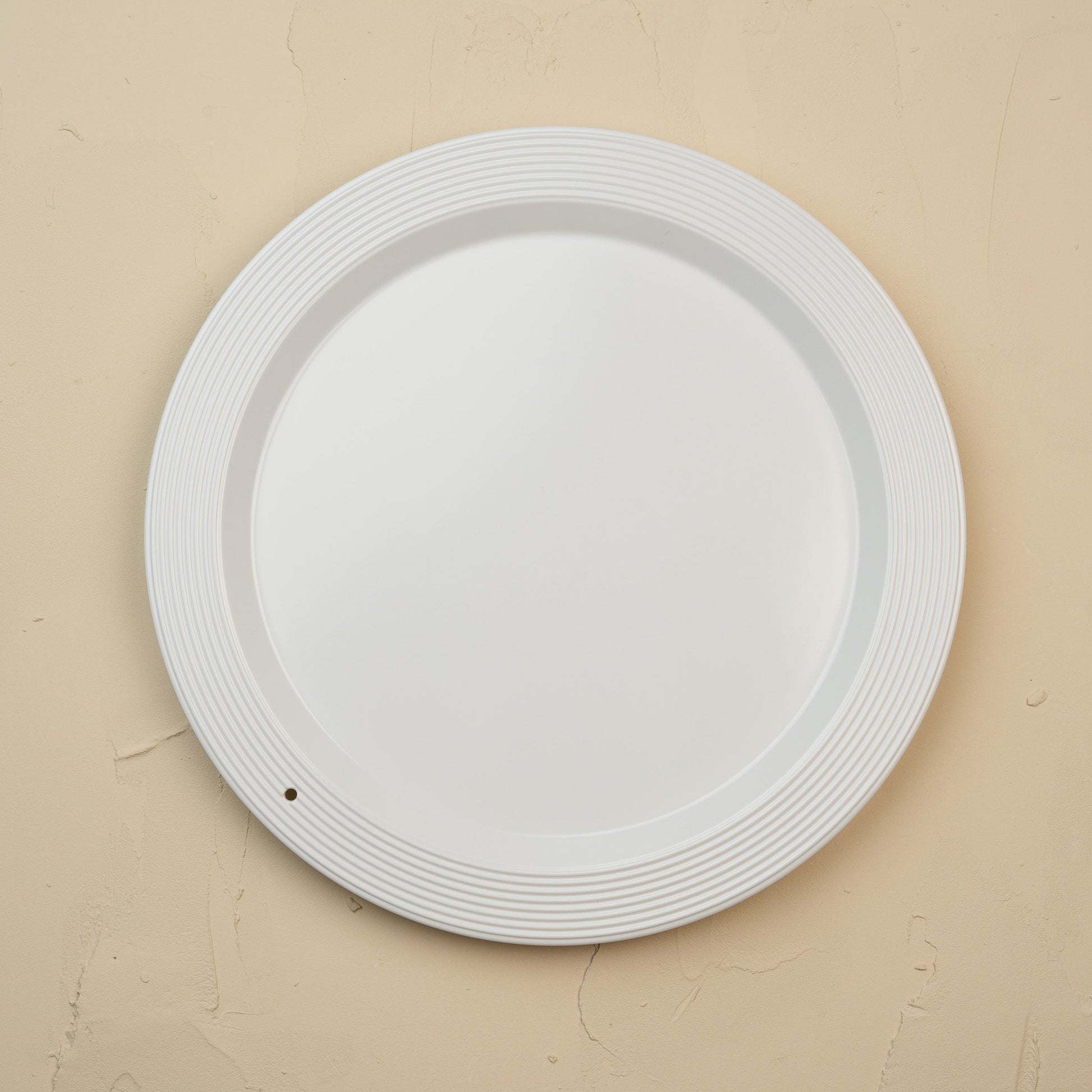 White melamine round platter on a beige background