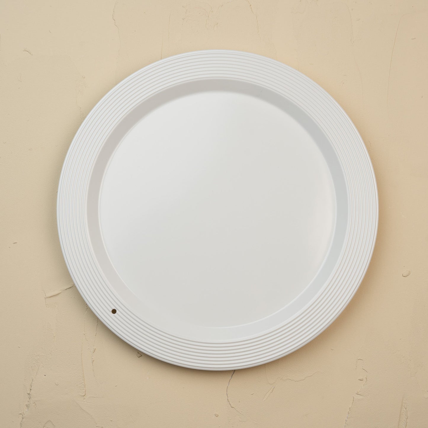 White melamine round platter on a beige background