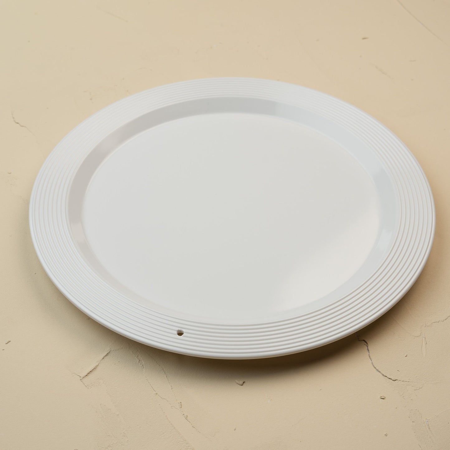 White melamine round platter on a beige background