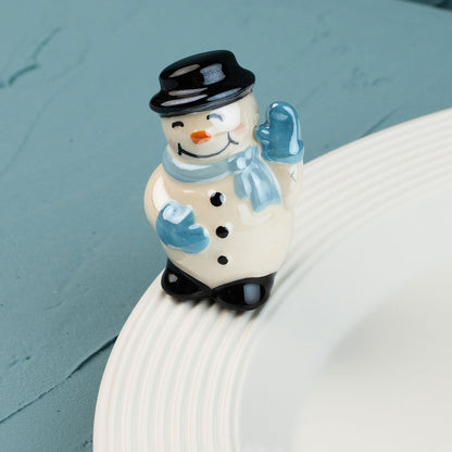 snowman mini with a black top hat, blue scarf, and gloves on a white plate against a teal background.