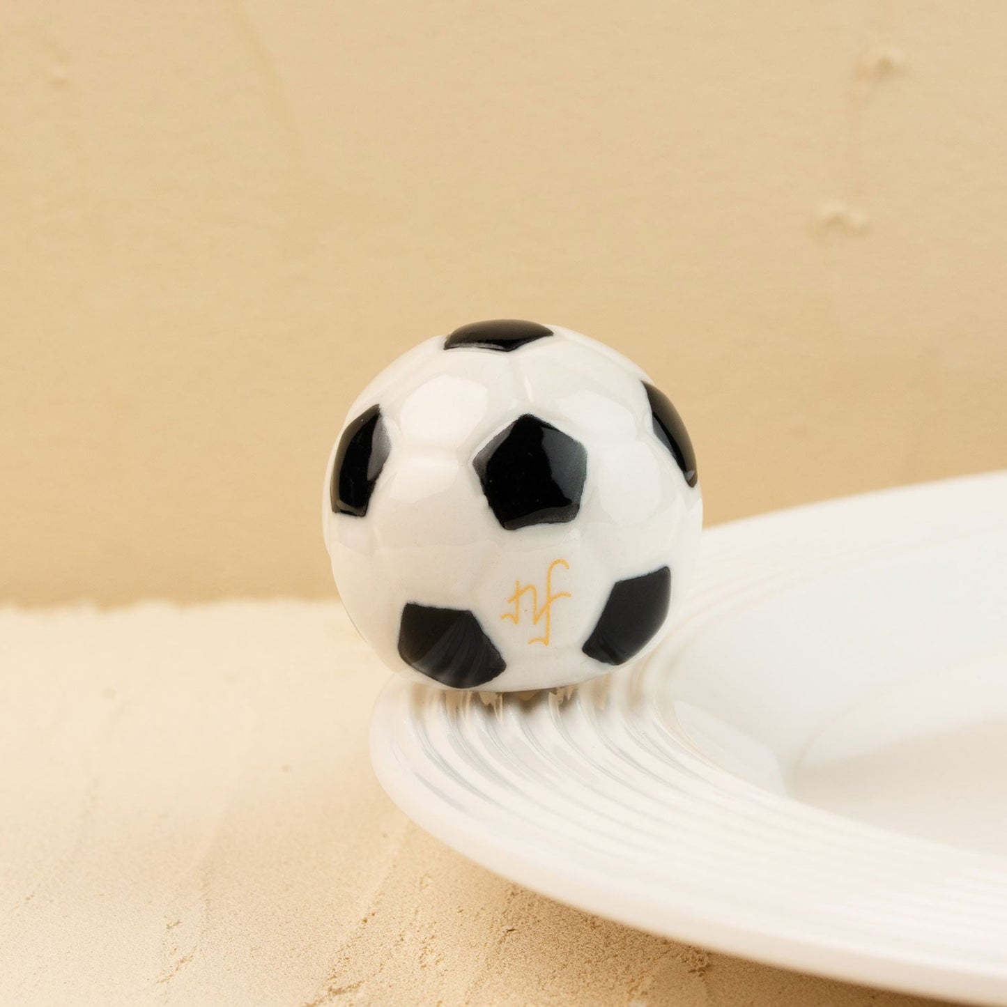 Black and white soccer ball mini t on a beige surface