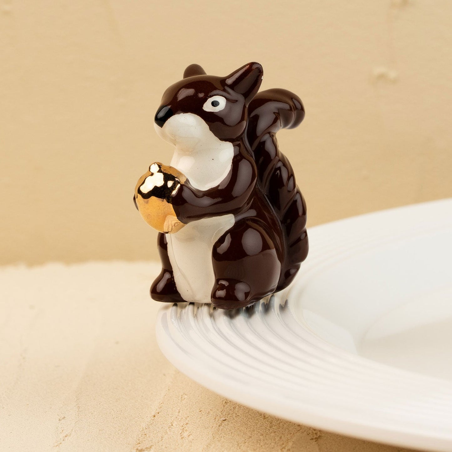Squirrel mini holding a nut on a beige background