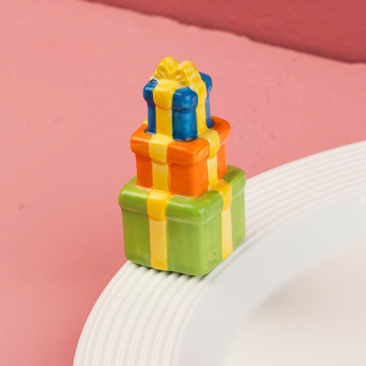 Colorful gift box-shaped mini on a white plate with a pink background