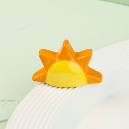 Sun-shaped mini with orange and yellow gradient on a white surface with a light green background