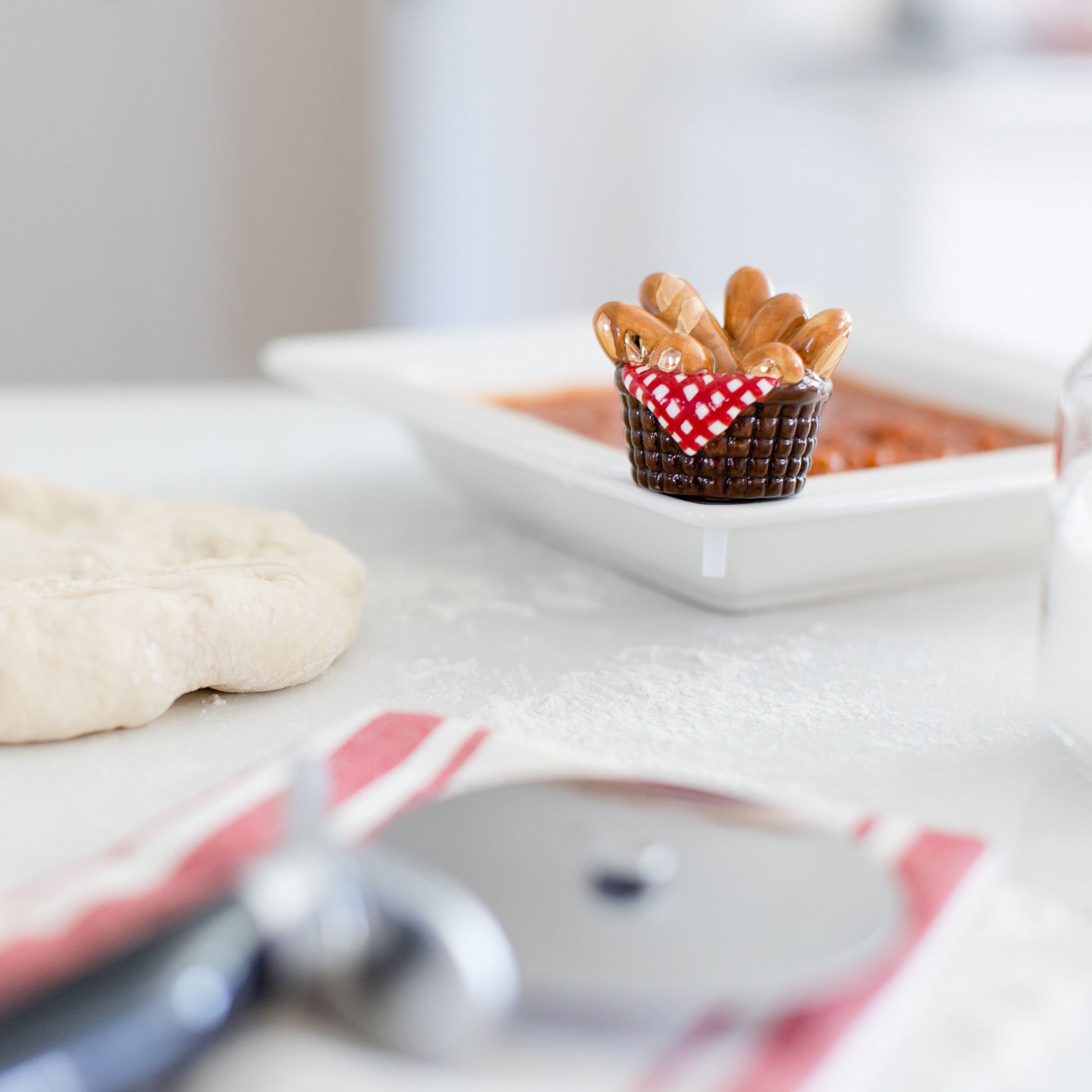 bread basket mini in a pizza-making setting with pizza dough and a pizza cutter.
