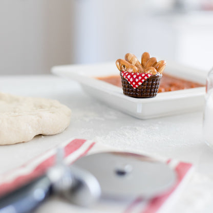 bread basket mini in a pizza-making setting with pizza dough and a pizza cutter.