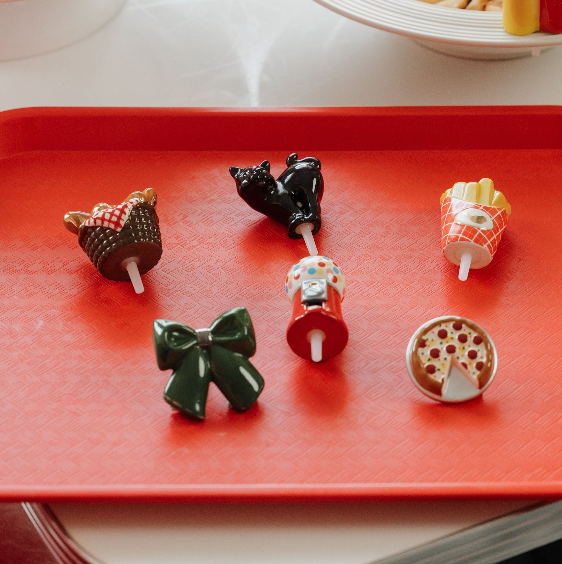 diner setting with a tray filled with bread basket mini, black cat mini, green bow mini, gumball mini, french fry mini and pizza mini. Behind the tray is a bowl of french fries and a mustard and ketchup mini.